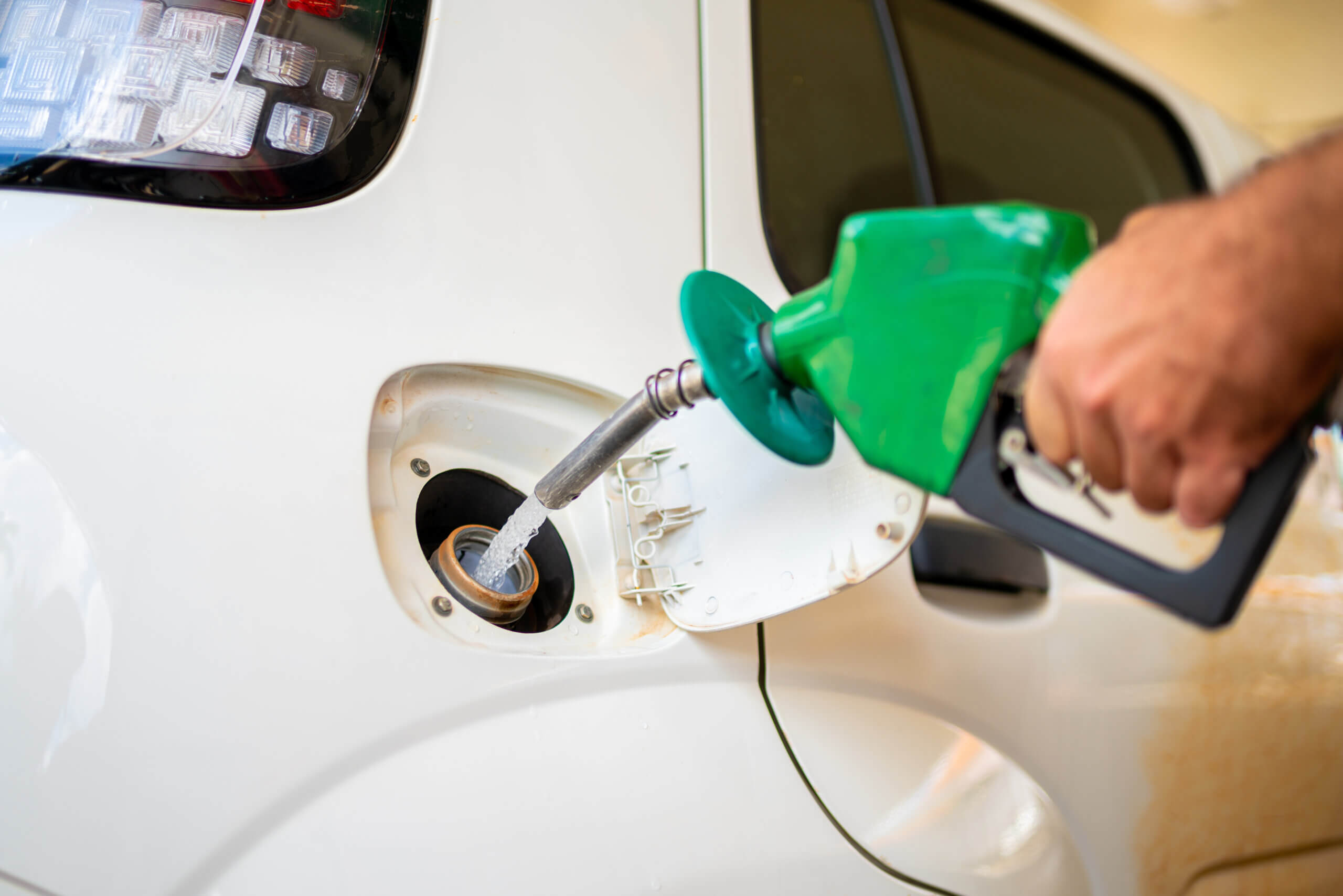 Closeup of man pumping gasoline fuel in car at gas station